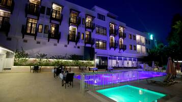 En säsongsöppen utomhuspool, parasoller och solstolar