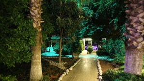 Un sendero bordeado de árboles y un jardín cuidado.