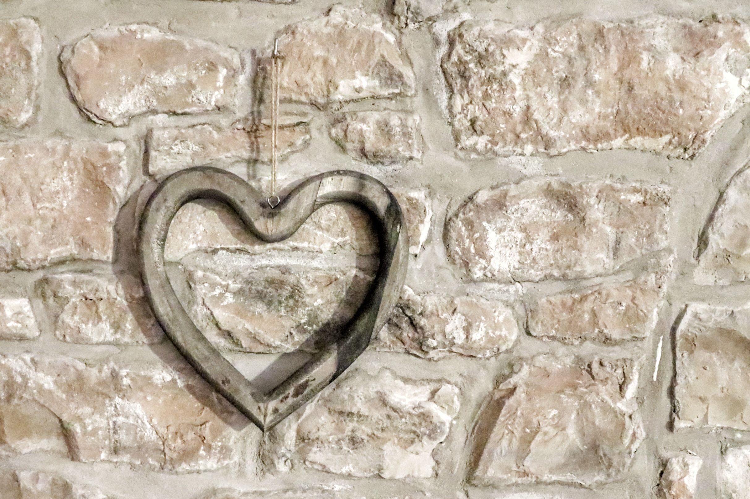 A heart-shaped metal decoration on a stone wall.
