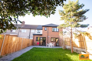 Enjoy outdoor dining and relaxation on the patio, surrounded by a beautifully manicured lawn and a charming fence.