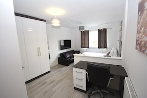 Relax in a spacious bedroom with a large wardrobe, comfortable sofa, and a neatly made bed with a white headboard.