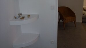 A white interior with a built-in shelf unit, a framed picture on the wall, and a wicker chair in the background.