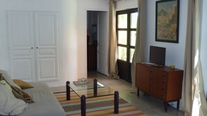 A bedroom with a bed, a dresser, a television, and a window with curtains.