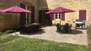 A stone building with a courtyard featuring outdoor seating and a barbecue grill.