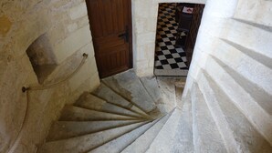 A stone staircase with a wooden door at the top, leading to a room with a checkered floor.