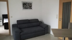 Una sala de estar moderna con un sofá gris oscuro, una mesita y un cuadro enmarcado en la pared.