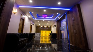 Una hall moderna con divani in pelle nera, una reception e un lampadario decorativo al soffitto.