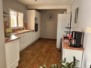 A kitchen with white cabinets, a coffee maker, and a wall clock.