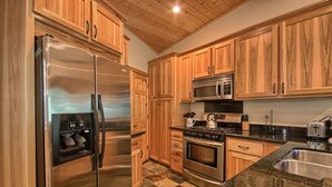 Una cocina con armarios de madera, electrodomésticos de acero inoxidable, encimeras de granito y piso de baldosas a cuadros.