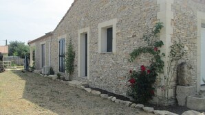A stone building with a row of windows and a garden with red flowers.