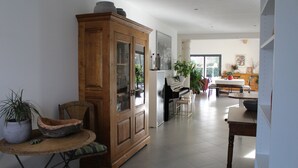 A spacious living area with a piano, a wooden cabinet, and a dining table.