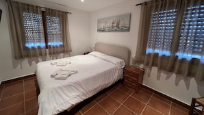 A hotel room with a bed, a nightstand, a painting on the wall, and curtains with a light pattern. - Villa 500m from the beach. Private pool.  (Teulada)