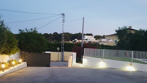 A gated parking area with a white fence, a metal gate, and a paved surface. - Villa 500m from the beach. Private pool.  (Teulada)