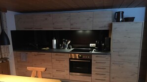 A compact kitchen with wooden cabinets, a built-in oven, a coffee maker, and a sink. - Quaint apartment in farmhouse (Schröcken)
