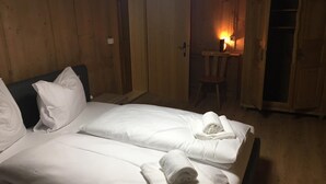 A room with two beds, a chair, a desk, and a lit lamp. - Quaint apartment in farmhouse (Schröcken)