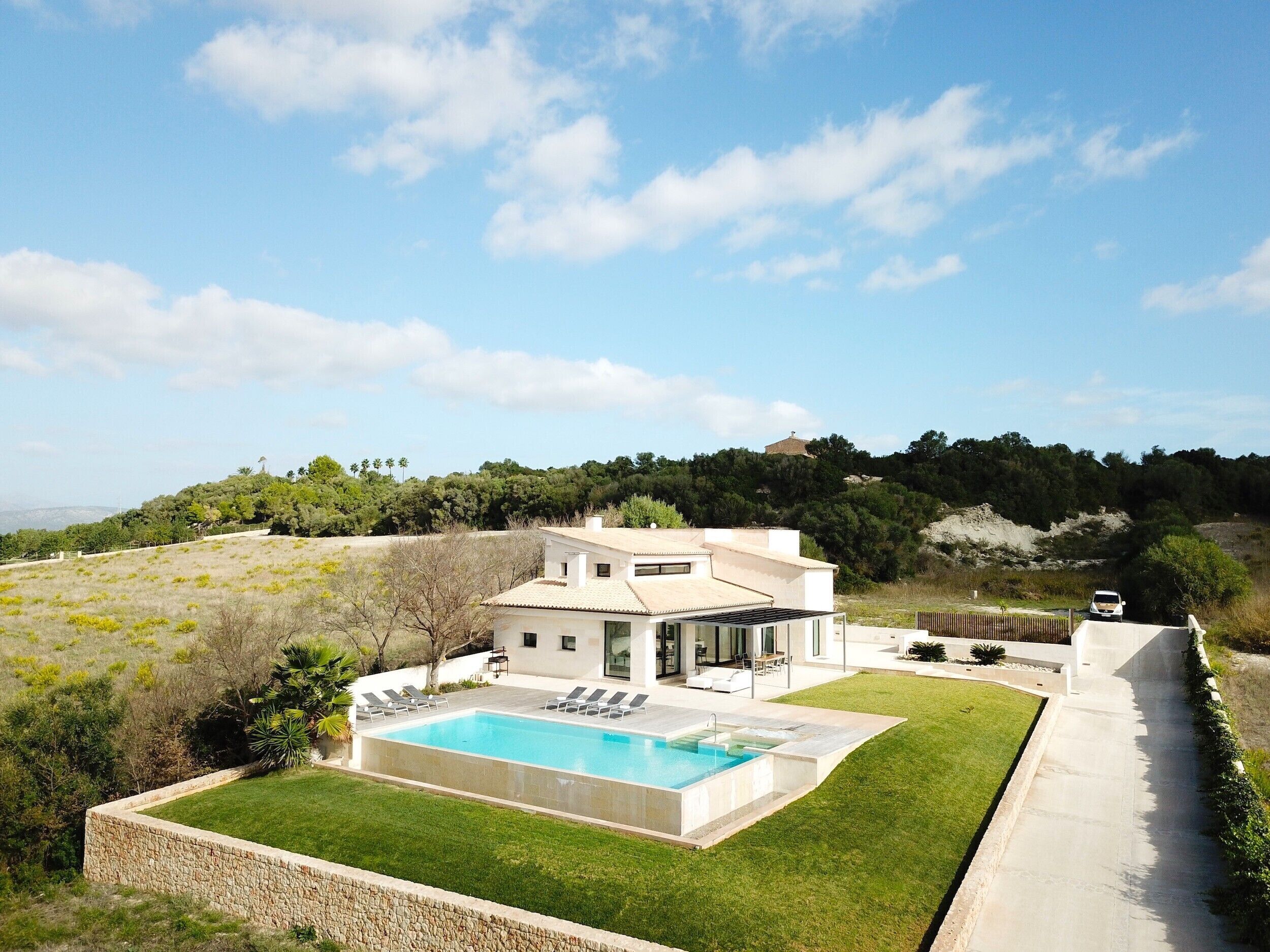 Une maison moderne dotée d’une piscine, d’un patio et offrant une vue sur le paysage environnant.