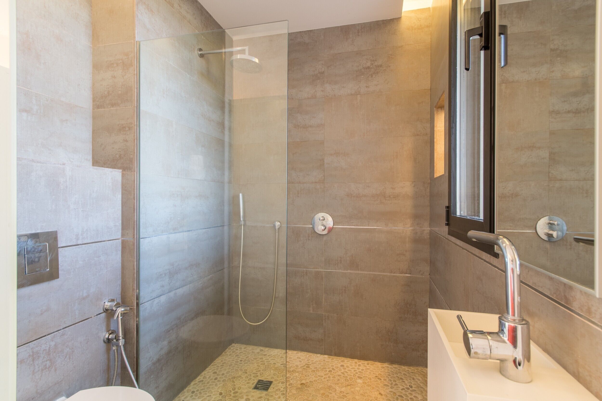 A modern bathroom with a glass-enclosed shower, a standalone sink, and a large mirror.