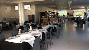 A spacious restaurant with multiple tables set for dining, a bar area, and a view of the outdoors. - Hotel Aurora (Porto Cesareo)