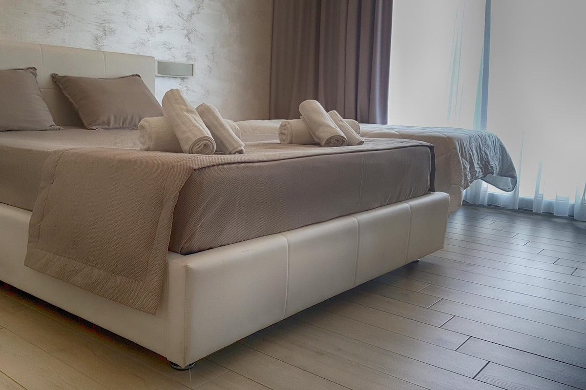 Un dormitorio moderno con una cama grande, una mesita de noche y vistas al exterior.