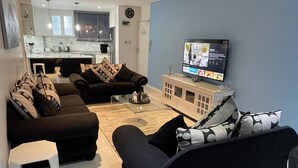 A modern living room with a sofa set, a TV, and a small white stool. - A fantastic modern and spacious apartment right on Umhlanga main Beach . (Umhlanga)