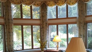 Eine gemütliche Leseecke mit rundem Tisch, einer Lampe und einer Bank mit Bücherregalen.