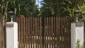 Une entrée fermée par un portail, précédée d’un chemin pavé de pierres claires et foncées disposées en damier.