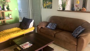 A living room with a brown sofa, yellow couch, and a coffee table with books and a remote control. - Villa with Caribbean Sea Small Pool (Les Trois-Îlets)