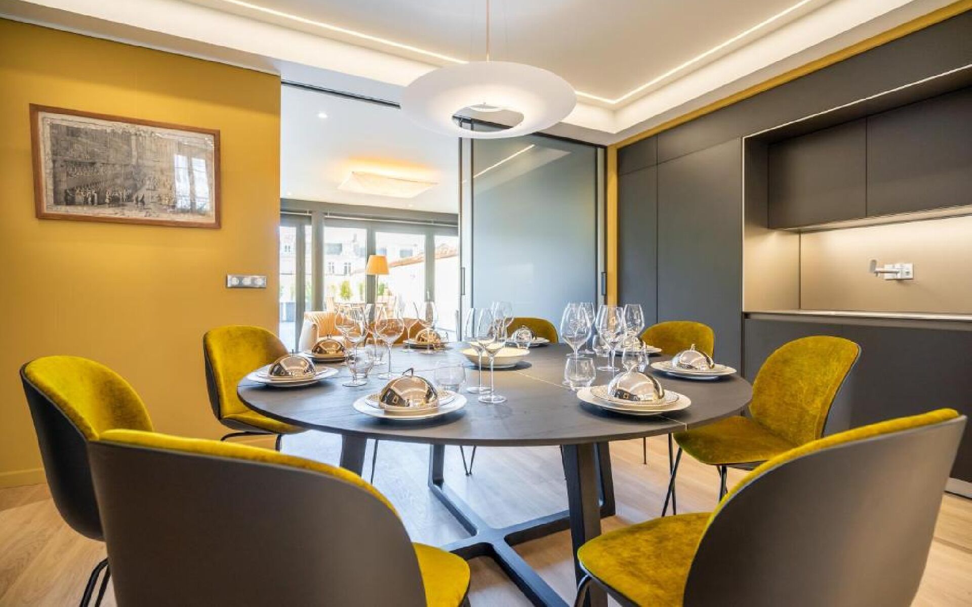 Un espace repas moderne avec une table ronde pour six personnes, entourée de chaises jaunes.