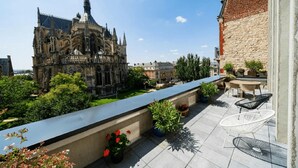 Una terrazza sul tetto con vista su un edificio storico, arredi da esterno e vasi di piante.
