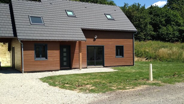 Un bâtiment moderne à deux étages, doté d’un toit en pente, de grandes fenêtres et d’une allée gravillonnée.
