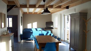 Une pièce spacieuse avec une table à manger en bois, des chaises bleues, un canapé et un téléviseur.