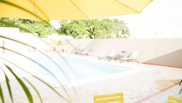 Zona de piscina con sillas de descanso y una sombrilla amarilla.