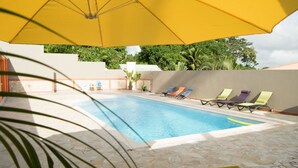Una piscina con sillas de descanso y un paraguas amarillo.