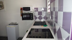 Cocina compacta equipada con microondas, horno tostador y refrigerador pequeño.