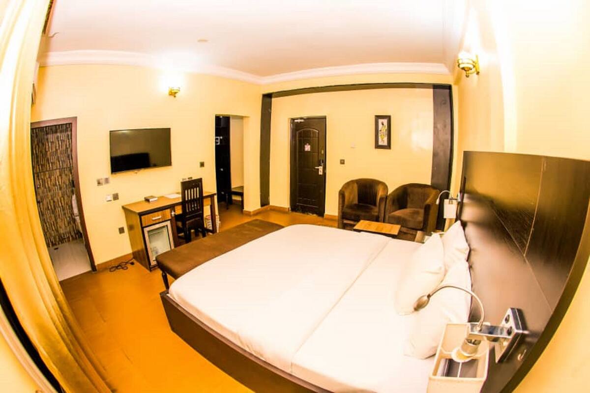 Une chambre d’hôtel avec un grand lit, un bureau, une chaise, une télévision et une porte.