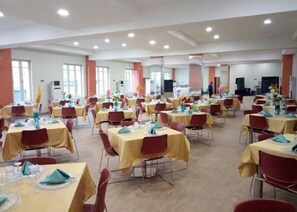 A large banquet hall with multiple tables set for dining, arranged in rows. - Nandas Hotel (Sagamu)