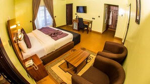 Una habitación de hotel con cama, escritorio, silla, televisor y armario.