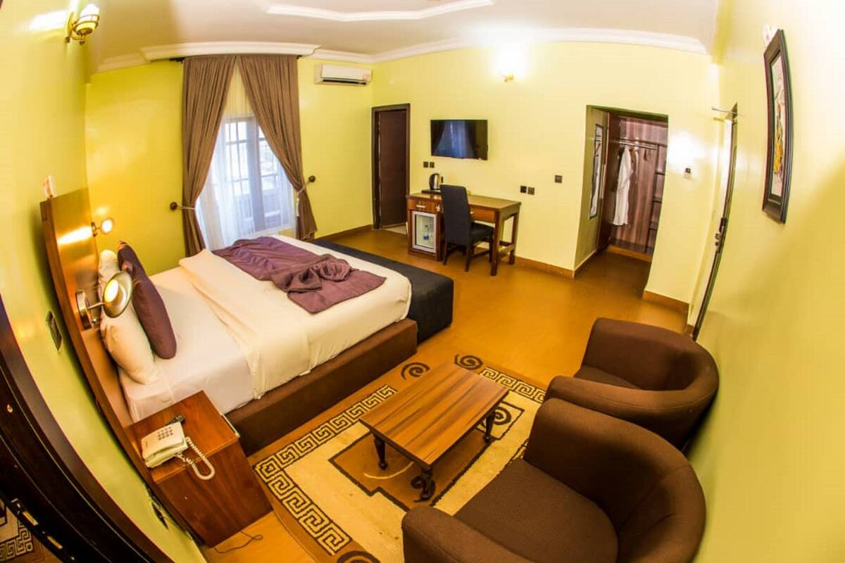 Une chambre d’hôtel comprenant un lit, un bureau, une chaise, une télévision et une armoire.