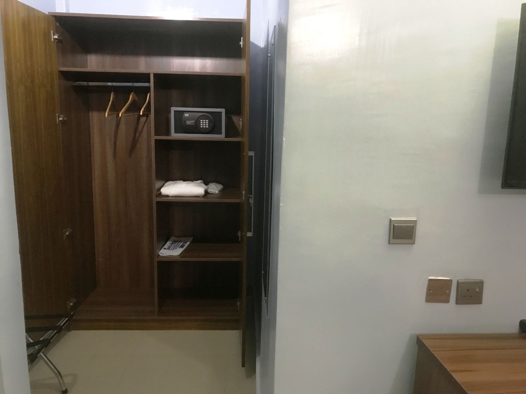 A wooden closet with a built-in safe, shelves, and hanging space.