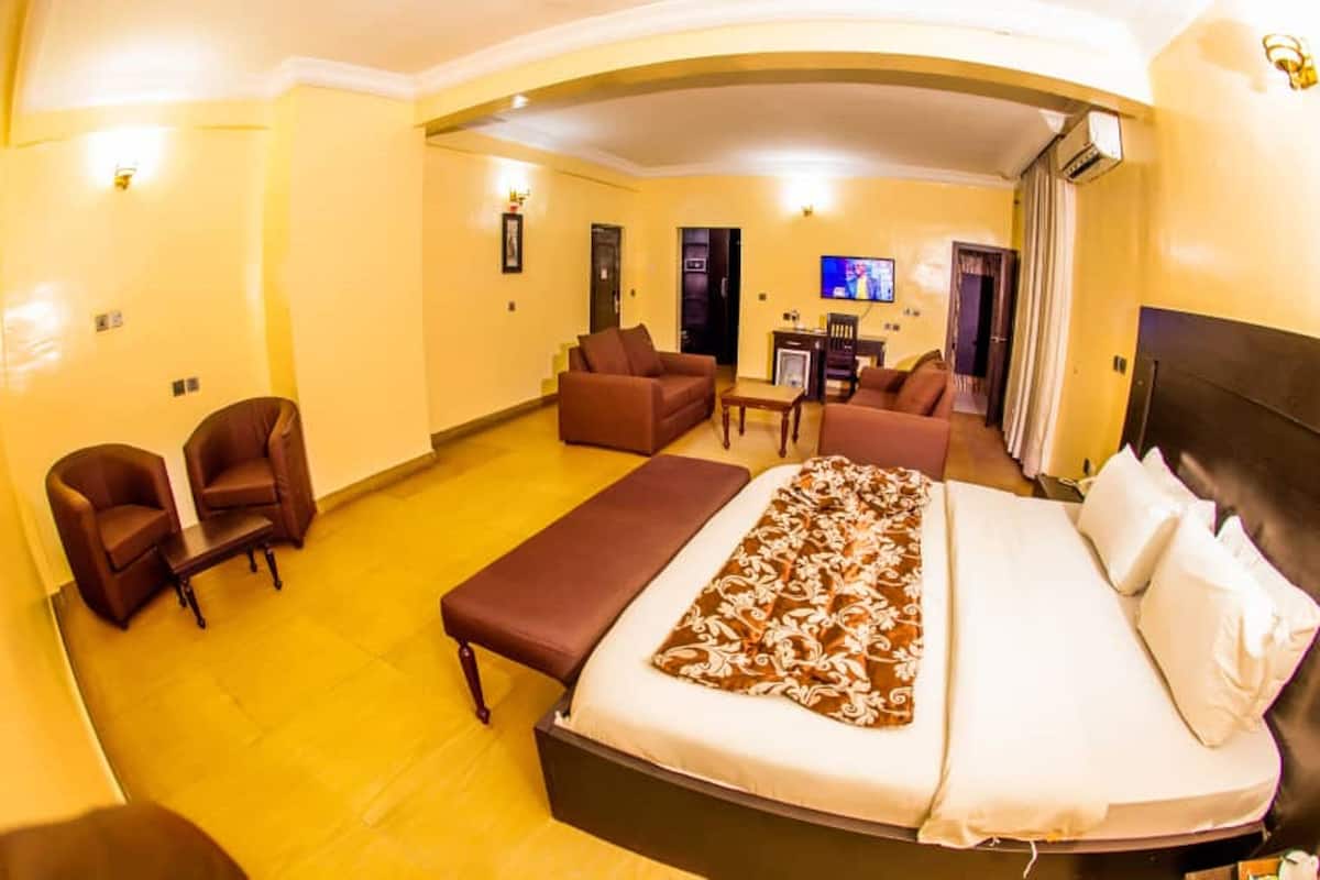 Une chambre d’hôtel avec un lit, deux canapés, une petite table et un téléviseur.