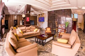 A spacious lobby with a large sofa set, a coffee table, and a television mounted on the wall. - Nandas Hotel (Sagamu)