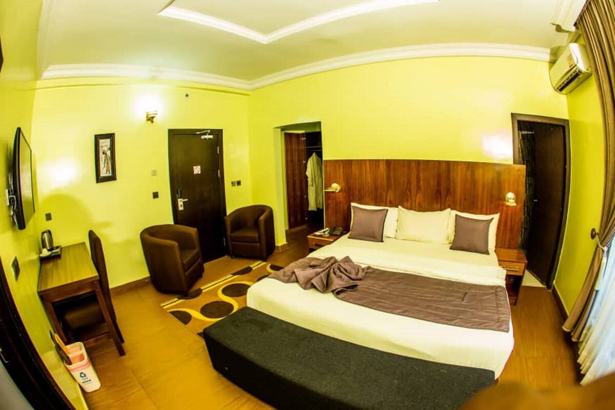 Une chambre d’hôtel avec un grand lit, un bureau, une chaise et un téléviseur.