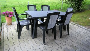An outdoor patio with a table and chairs, surrounded by a garden and a fence. - Family-friendly apartment on the Hofsteig (Schwarzach)