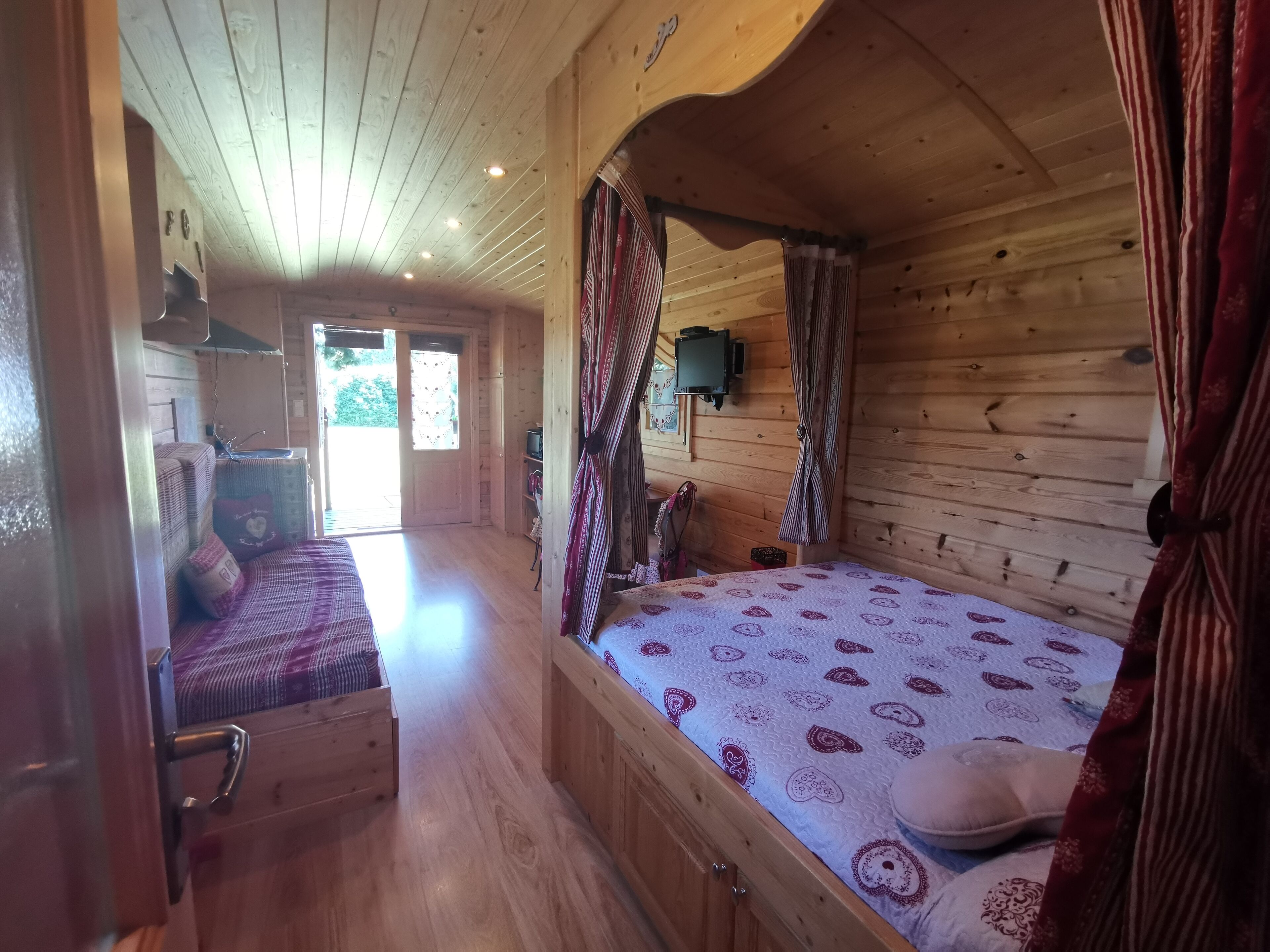 Una habitación de cabaña de madera con una cama, un banco y un televisor.