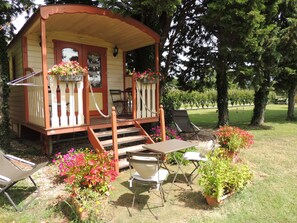A wooden cabin with a porch, a dining table, and outdoor seating. -  THE ROULOTTE DU SOLEIL  (Eyragues)