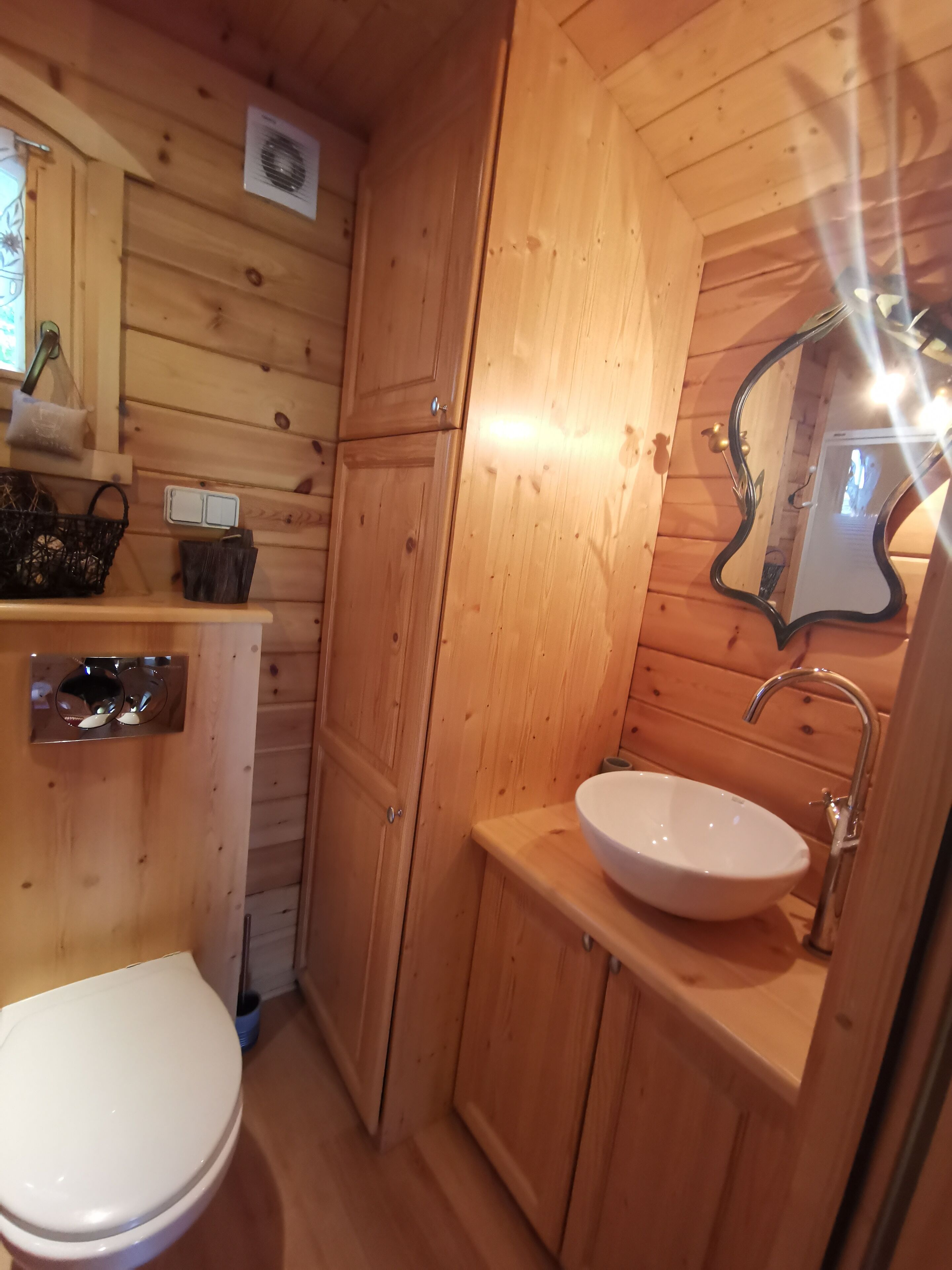 Une petite salle de bain en bois, avec un lavabo blanc, un miroir et des toilettes.