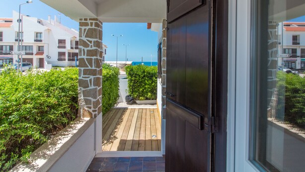 Ein Balkon mit einer Steinsäule, Holzboden und Blick auf das Meer.