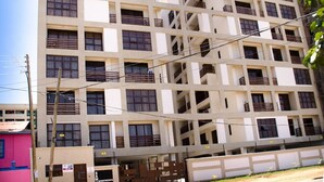 A multi-story building with a grid-like facade, balconies on each floor, and a visible entrance with signage. - Zawiya property (Nairobi)