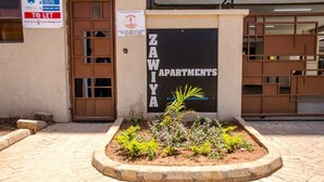 A building with a sign for ZAWIYA APARTMENTS, a security notice, and a Hyra Real Estate sign. - Zawiya property (Nairobi)