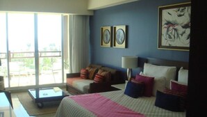 A hotel room with a bed, a sofa, a desk, and a balcony with a view.